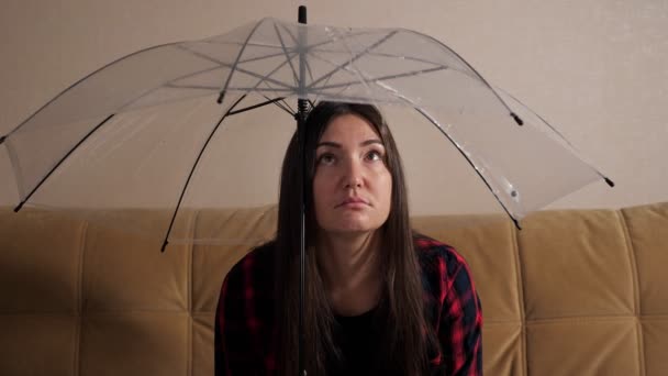 Pensive woman hides from flowing water under clear umbrella — Stock Video