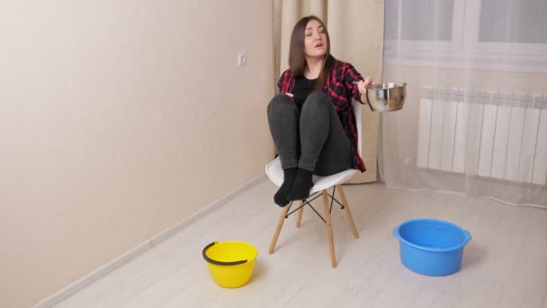 Mujer molesta recoge el agua que baja del techo en la habitación — Vídeo de stock