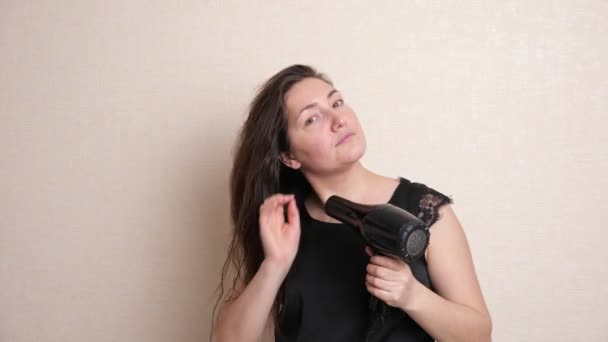 Mooie en rustige dame geniet van het drogen van haar met moderne styler — Stockvideo