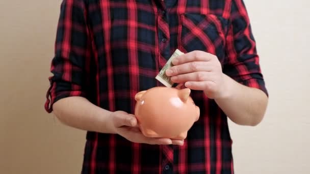 Frau hält Sparschwein auf Handfläche und wirft Geldschein hinein — Stockvideo