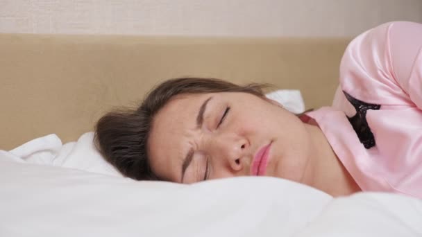 Леди лежит в постели закрывая ухо подушкой — стоковое видео