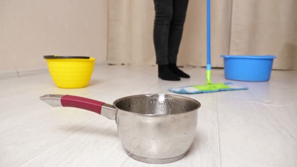 Water flows into pot from ceiling while woman mops floor — Stock Video