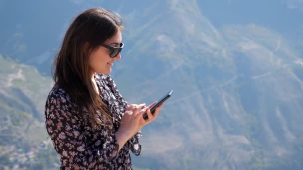 선글라스를 낀 행복 한 여성은 고 지대에서 스마트폰을 사용 한다 — 비디오
