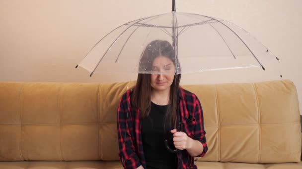 Pensive woman hides from flowing water under clear umbrella — Stock Video