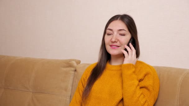 Ung kvinna med långt löst hår pratar på smartphone hemma — Stockvideo