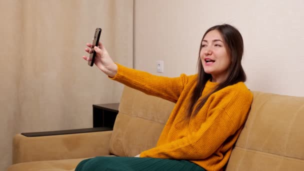 Giovane bruna tiene smartphone e posa nella fotocamera anteriore — Video Stock