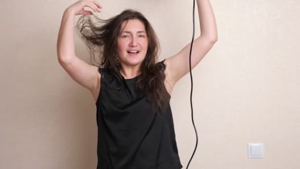 Lady sostiene el secador de pelo en la mano y se seca bailando y cantando — Vídeos de Stock