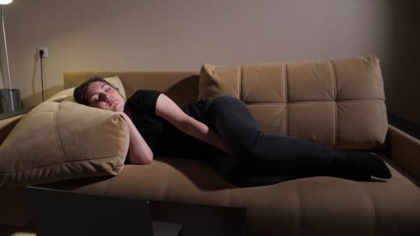 Young woman lies on brown sofa with large pillows and sleeps — Stock Video