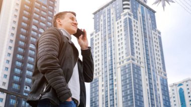 Sonbahar deri ceketi giyen bir işadamı akıllı telefon konuşur.