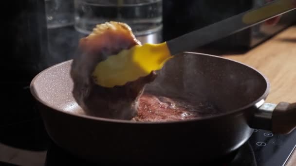 Chef retourne les steaks poêlés avec des pinces jaunes — Video