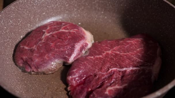 Gros plan de deux steaks rouges dans une poêle — Video