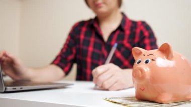 Bulanık kadın, pembe kumbaranın yanındaki çocuk harcamalarını sayıyor.