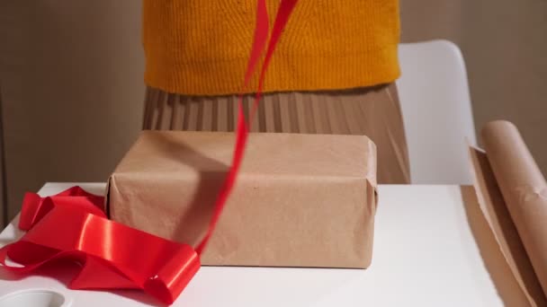 Неузнаваемая женщина украшает подарочную коробку красной лентой — стоковое видео