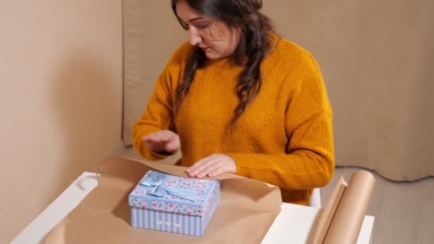 Junge Frau packt Geschenkbox in Kraftpapier — Stockvideo