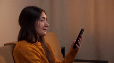 Kazaklı esmer koltukta oturur ve akıllı telefonda yazar.