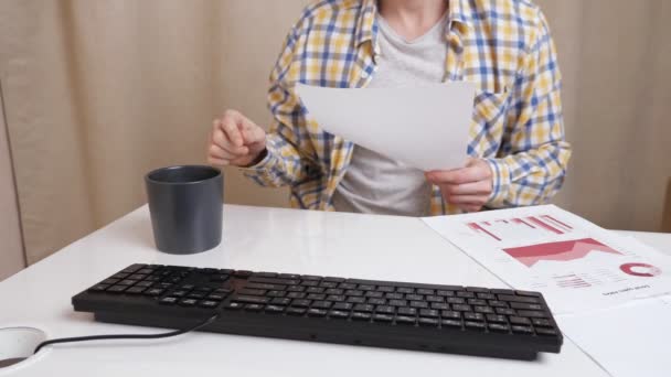 Hombre irreconocible trabaja con documentos y tipos de texto en el teclado, arroja café sobre la mesa — Vídeo de stock