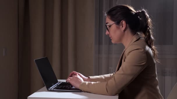 Pretty brunette with ponytail types on laptop at home — Stock Video