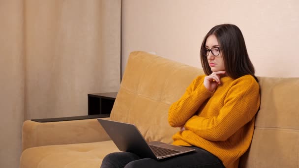 Allvarlig ung kvinna med långt löst hår sitter på laptop — Stockvideo