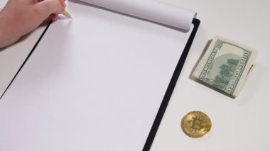 Kadınların elleri bir büyüme grafiği çizer, dolar ve bitcoin hemen yanında yer alır