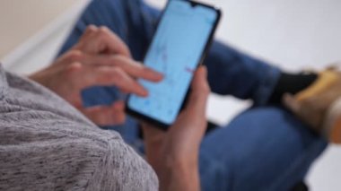 Telefonu olan tanınmayan bir adam borsa haritalarını inceliyor.