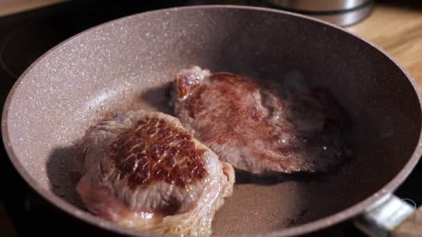 Dos jugosos filetes de ternera se fríen en una sartén, en cámara lenta — Vídeos de Stock