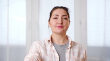 Gülümseyen kadın evin anahtarlarını pencerenin yanında gösteriyor.