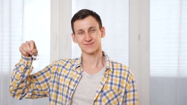 Mann im karierten Hemd schüttelt Schlüssel für neue Wohnung im Zimmer — Stockvideo