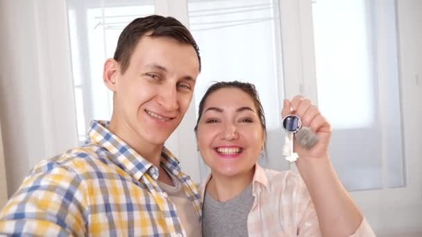 Szczęśliwa rodzina z kluczami nowego mieszkania sprawia selfie w pokoju — Wideo stockowe