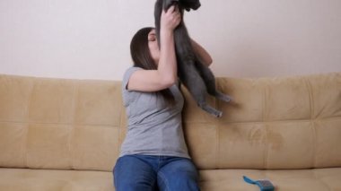 Uzun saçlı esmer, büyük kediyi dizlerinin üstüne çöktürür.