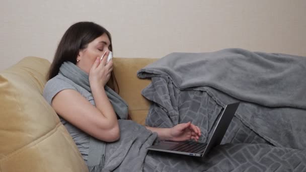 Mujer freelancer toses y tipos en el ordenador portátil tumbado en el sofá — Vídeos de Stock