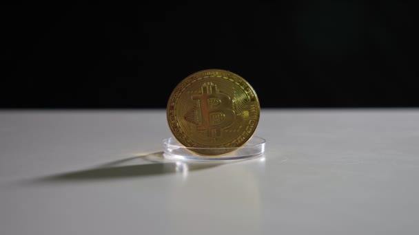 Zlatý bitcoin osvícený a odražený na bílém stole — Stock video