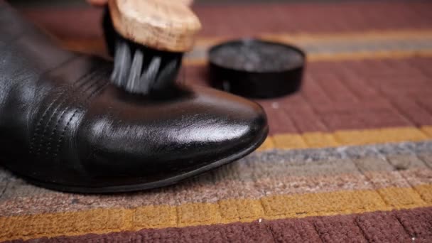 Close-up of a shoe brush rubs a black leather boot — Stock Video