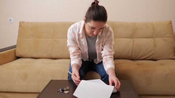 Mulher lê contrato de compra de apartamento à mesa no quarto — Vídeo de Stock