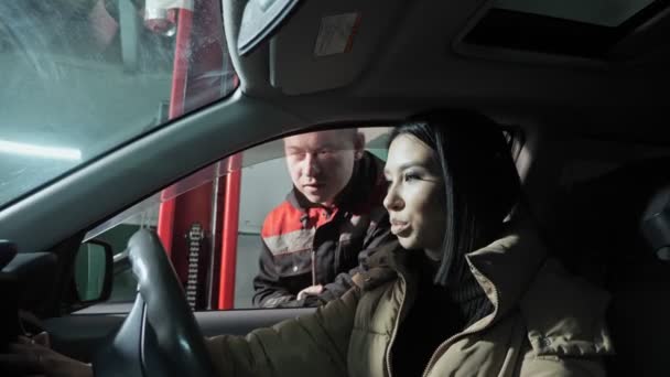 Mechaniker spricht Frau an, die im Auto am Bahnhof sitzt — Stockvideo