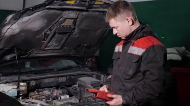 İşçi istasyonda otomobili kontrol etmek için dijital aygıt kullanır