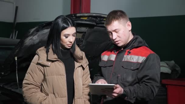 Technicien affiche la liste des prix sur tablette au client à la station — Video