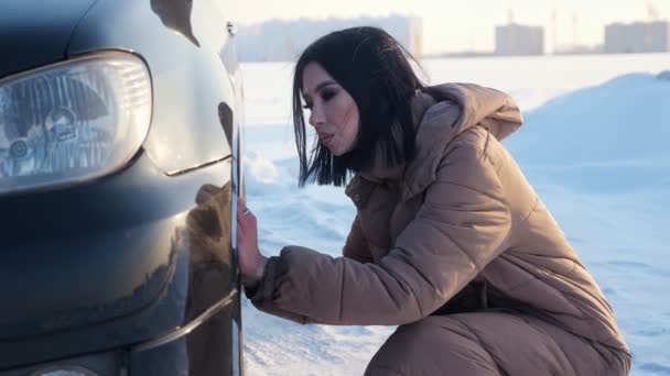 Pani sprawdza koło opony zepsutego samochodu na śnieżnej drodze — Wideo stockowe