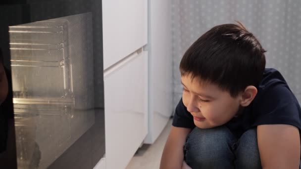 Αγόρι που κάθεται και κοιτάει μέσα στο φούρνο — Αρχείο Βίντεο