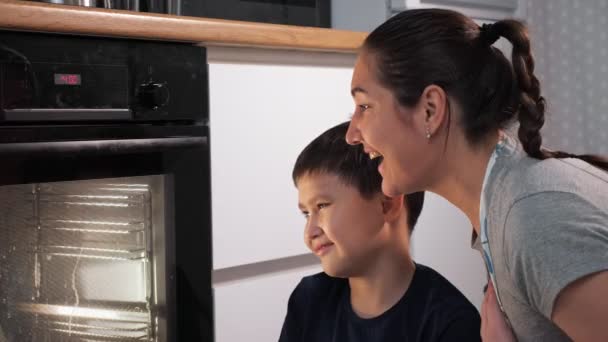 Mulher e menino olham para o forno enquanto esperam por um prato — Vídeo de Stock