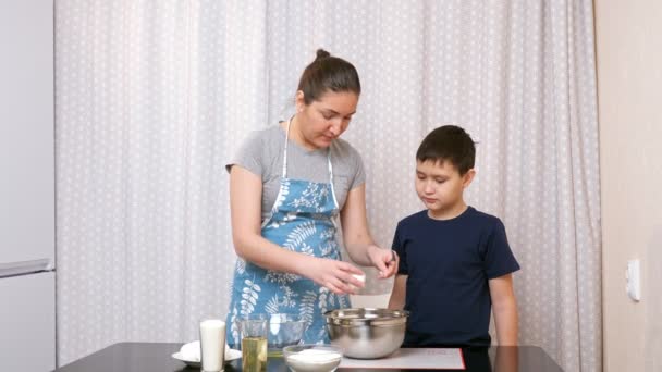 Frau lehrt Jungen, in der Küche zu kochen — Stockvideo