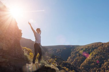 Kaslı adam silueti gün ışığında uçurumun kenarında duruyor.