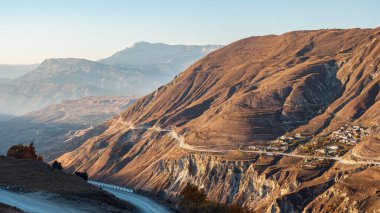 Boş yollar, yüksek antik dağların kahverengi yamaçları boyunca uzanıyor.