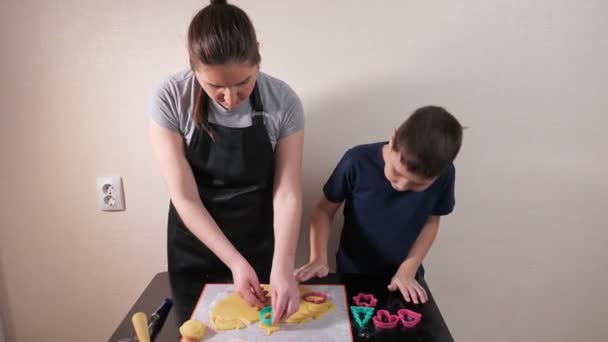 Νεαρή γυναίκα και αγόρι κόβουν διαφορετικά σχήματα από ζύμη — Αρχείο Βίντεο