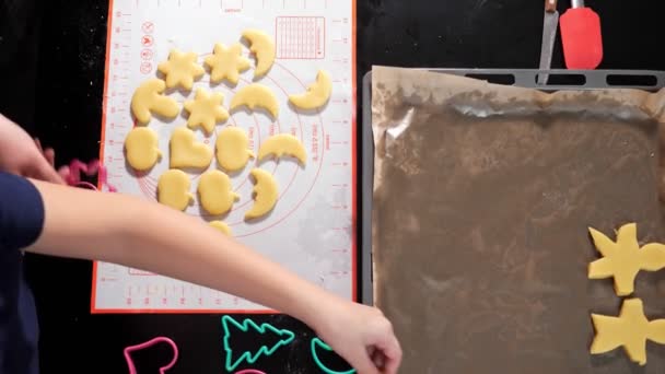 Unrecognizable woman and boy spread out dough of different shapes on a baking sheet slow motion — Stock Video