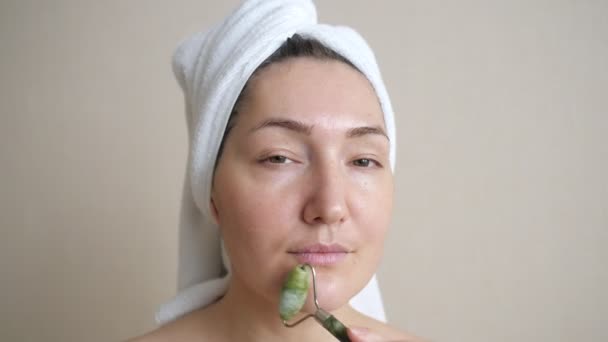 Detailní záběr ženy při masáži obličeje s nefritovým válečkem — Stock video