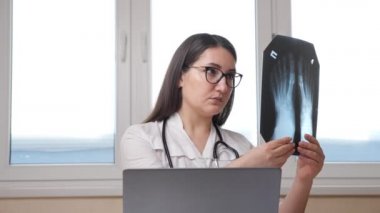 Gözlüklü doktor, ofisteki ayak röntgenlerini kontrol ediyor.