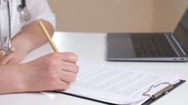 Doktor ofisteki masada panoda kağıtlarla çalışır.