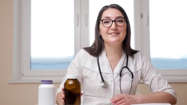 Femme gaie médecin montre des bouteilles avec des médicaments à la caméra — Video