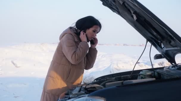 Mujer molesta mira el motor automático roto en el camino nevado — Vídeos de Stock