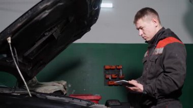 İşçi istasyonda otomobili kontrol etmek için dijital aygıt kullanır